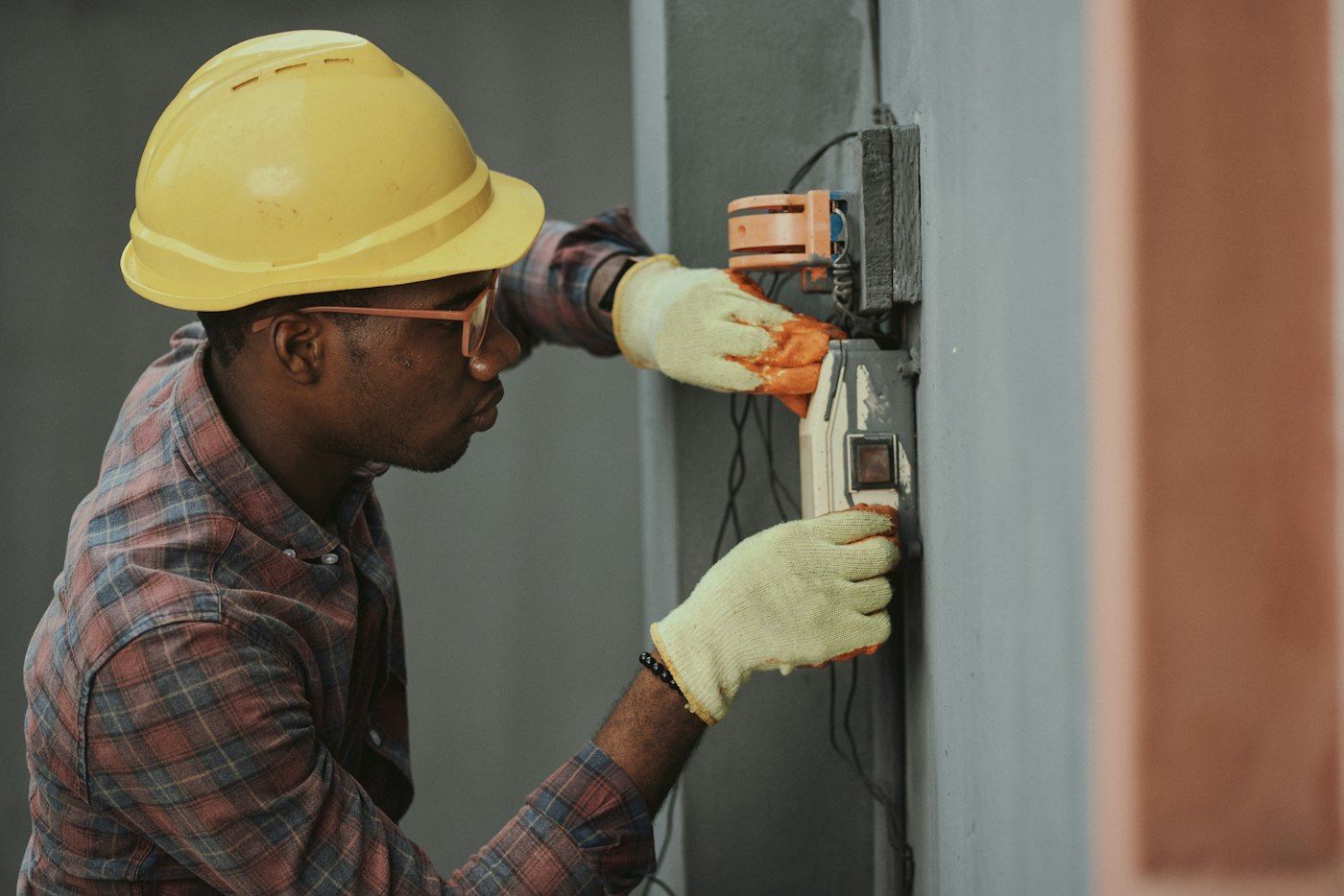 Handwerker in gelbem Helm prüft einen Sicherungskasten