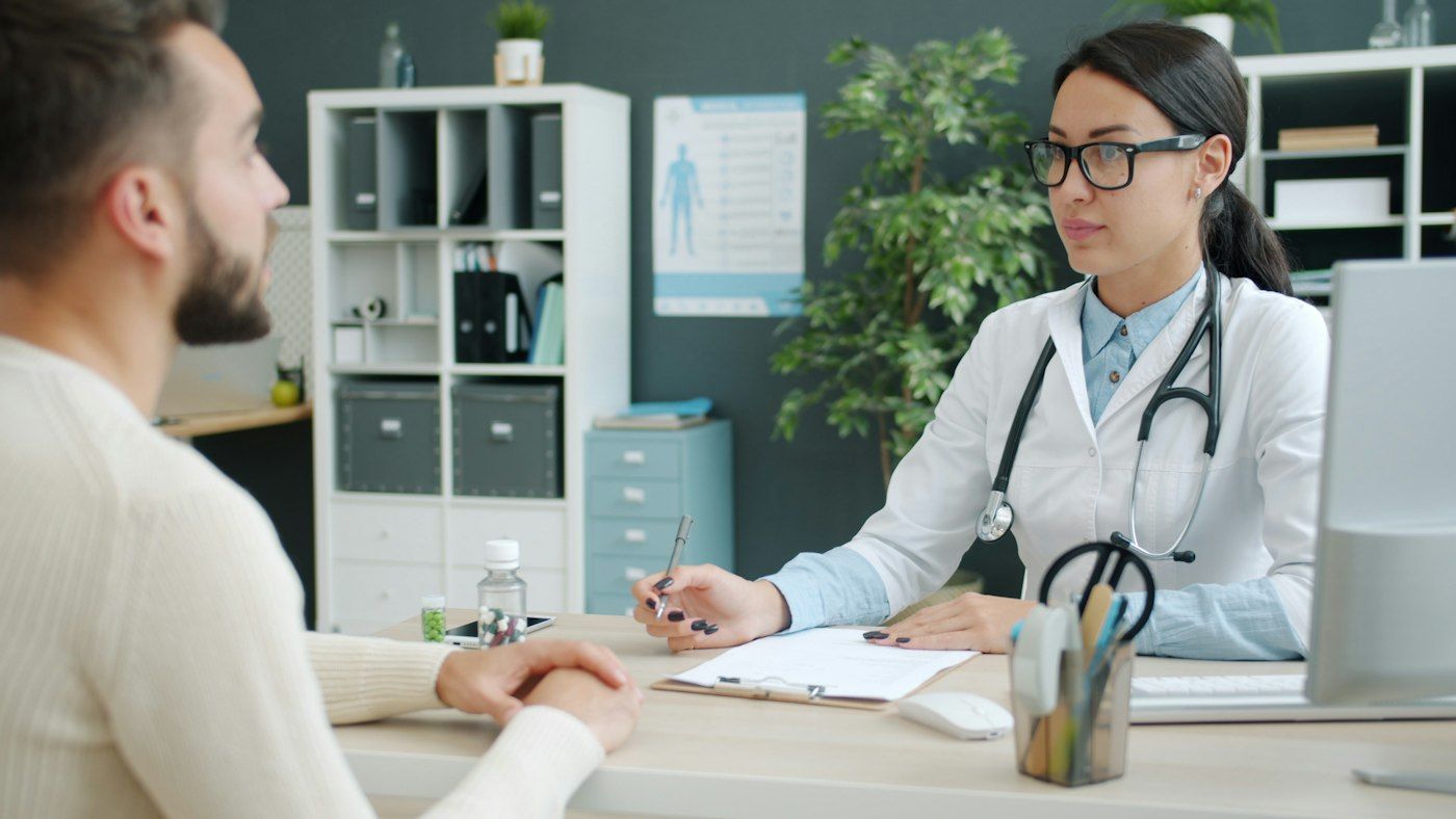 Ärztin im Gespräch mit einem Patienten am Schreibtisch